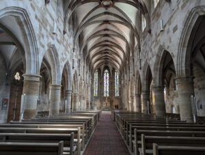 Innenansicht vom Münster St. Paul, einer gotischen Kirche. Perspektive vom Mittelgang Richtung Altar. Kirche sehr schlicht und karg gestaltet. Viel roher Stein.